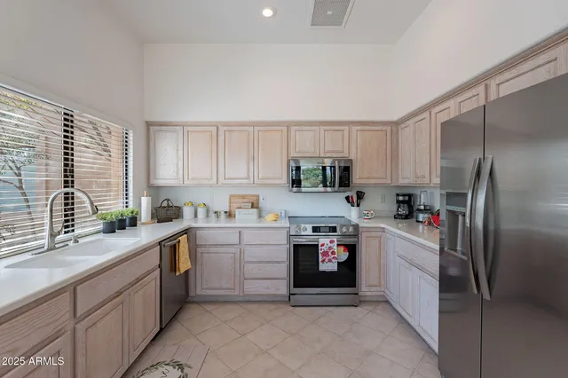 a kitchen with stainless steel appliances granite countertop a sink a stove a refrigerator cabinets and a window