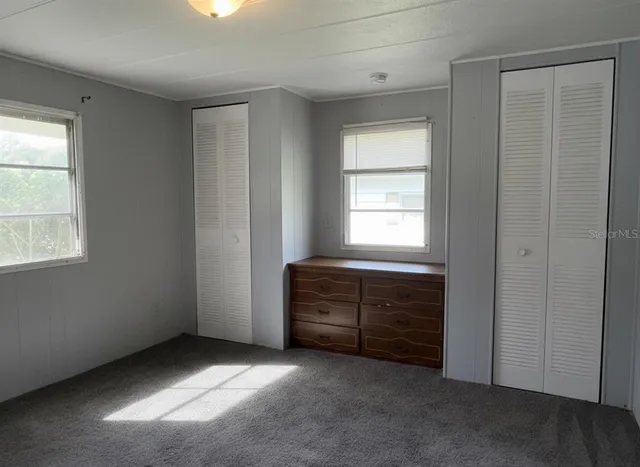 a view of an empty room with window and cabinet