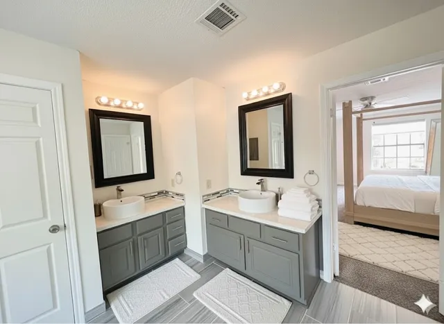 a bathroom with a double vanity sink mirror and bathtub