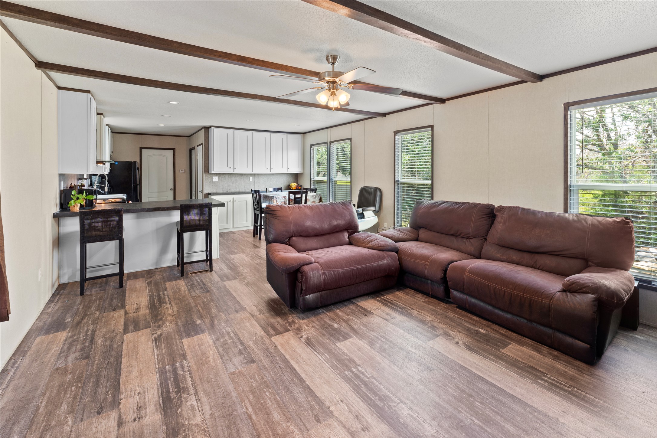109 Hibiscus Cove Elgin, TX 78621 - Photo 2 of 15 An open-concept layout unites the kitchen and living area, featuring rich wood-toned flooring and exposed beam ceilings.
