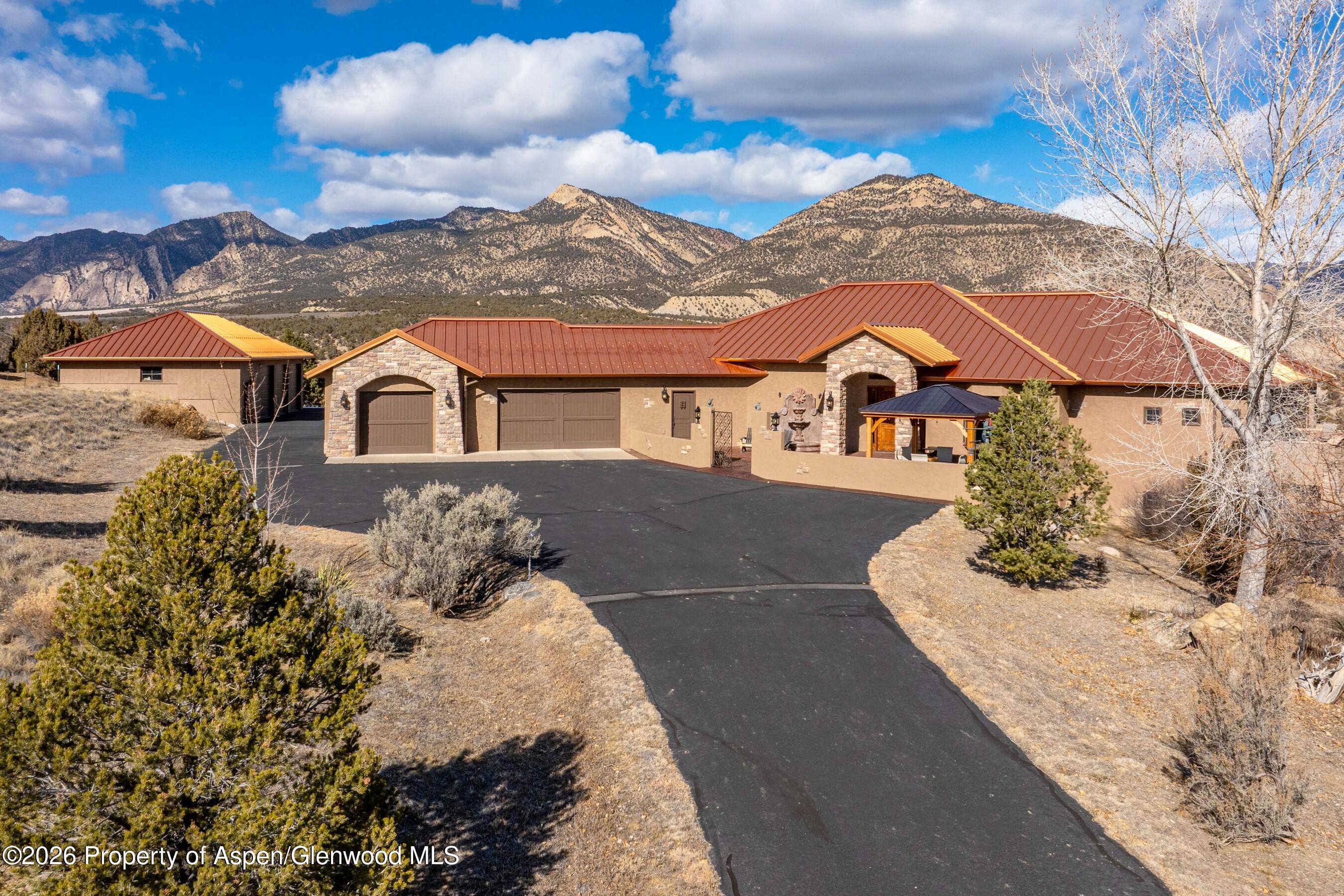 a view of a white house with a yard and table and chairs under an umbrella