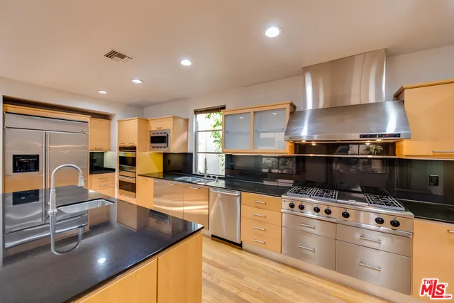 a kitchen with stainless steel appliances kitchen island granite countertop a stove and a sink