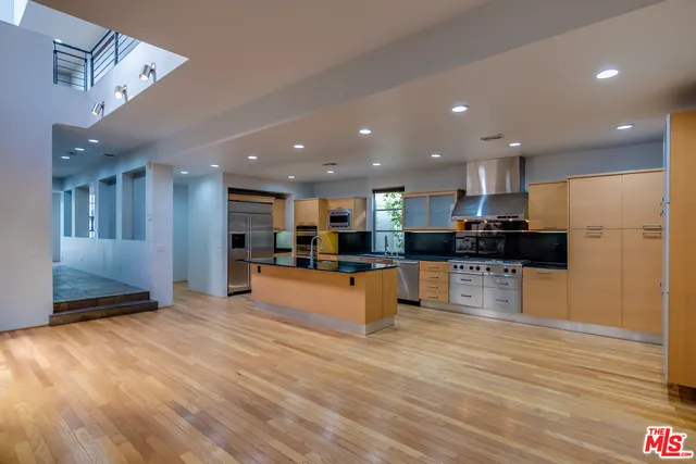 a large kitchen with stainless steel appliances kitchen island a large counter top and a wooden floors