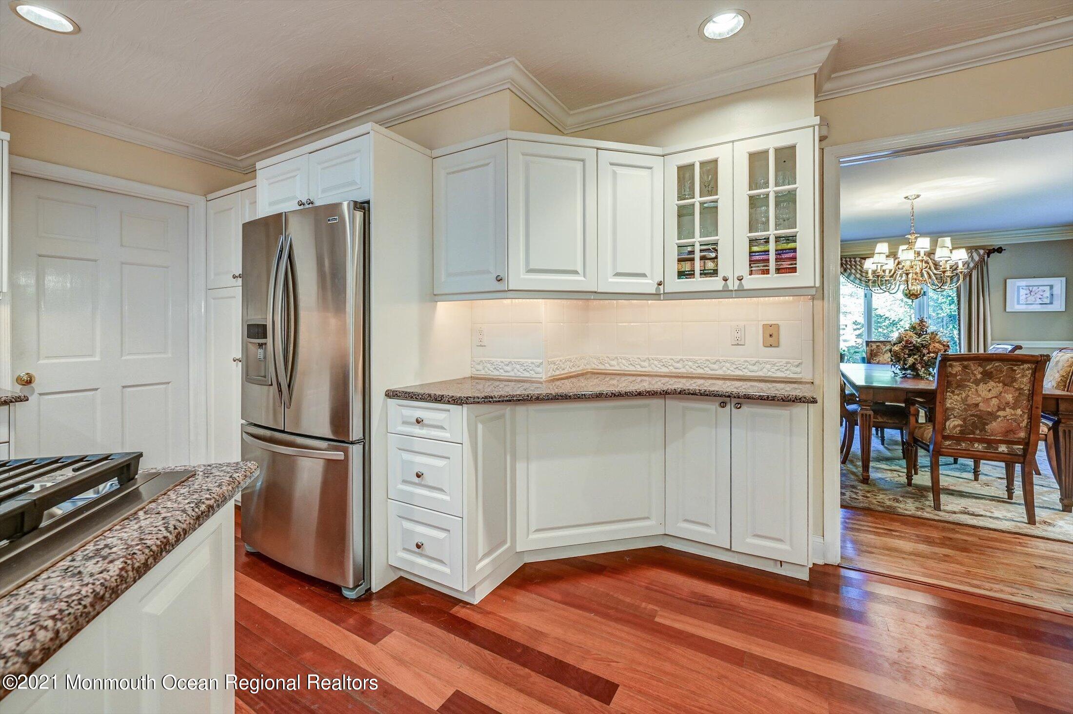 10 Crowfield Lane Holmdel, NJ 07733 - Photo 16 of 52 a kitchen with kitchen island granite countertop a refrigerator cabinets and wooden floor
