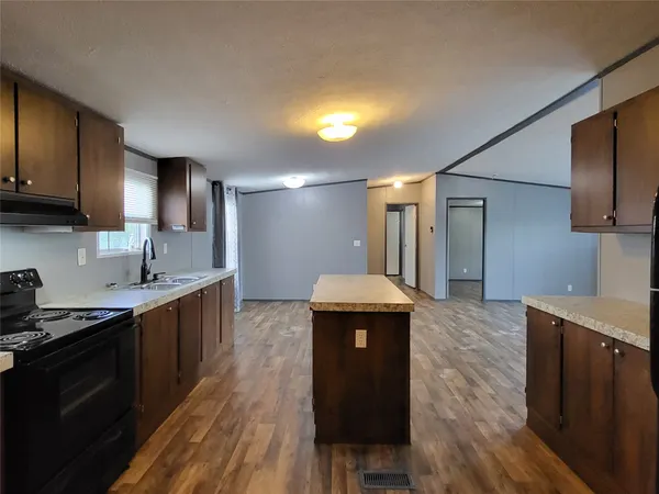 a kitchen with granite countertop a sink stainless steel appliances wooden floor and cabinets