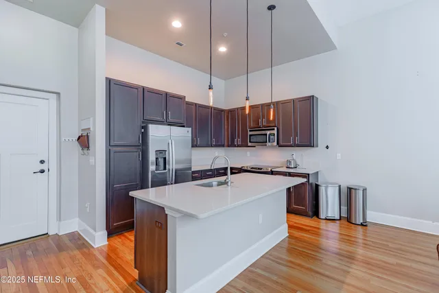 a kitchen with stainless steel appliances a sink a stove a refrigerator cabinets and wooden floor