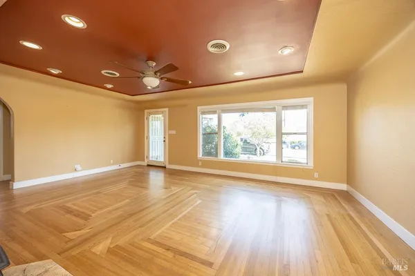 a view of an empty room with a window and wooden floor
