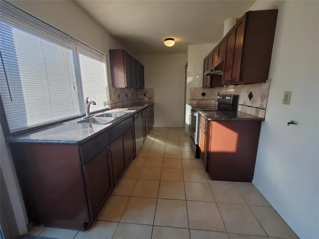 a kitchen with stainless steel appliances granite countertop a stove top oven a sink dishwasher and a refrigerator