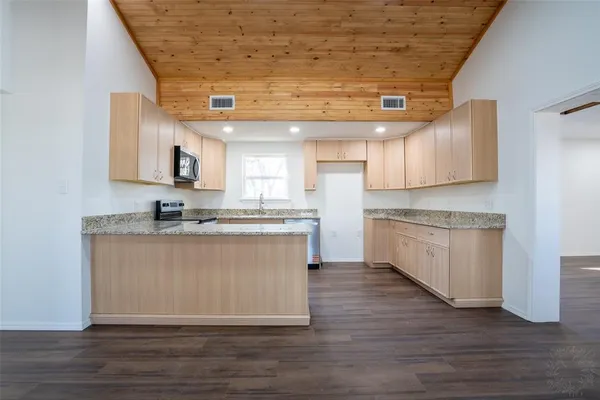 a large kitchen with stainless steel appliances granite countertop a stove a sink and a microwave