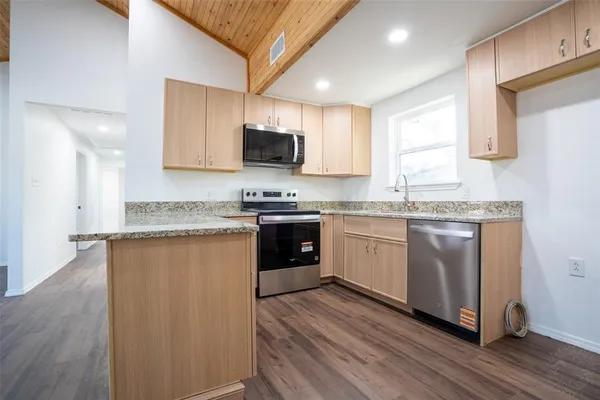 a kitchen with stainless steel appliances granite countertop a stove a sink dishwasher a microwave oven and a refrigerator with wooden floor