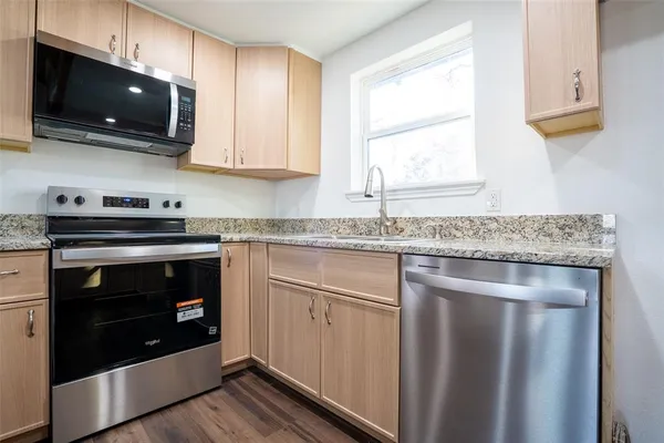 a kitchen with granite countertop a stove and a microwave