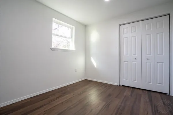 an empty room with wooden floor and closet area