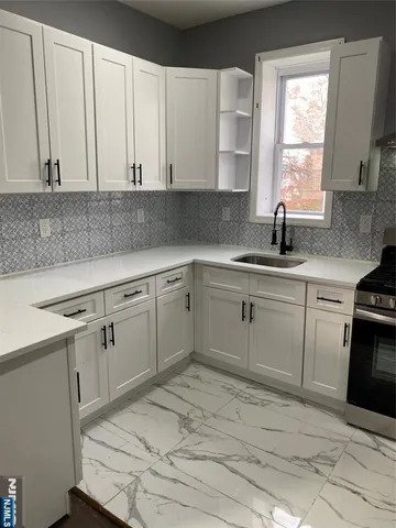 a kitchen with white cabinets appliances a sink and a window