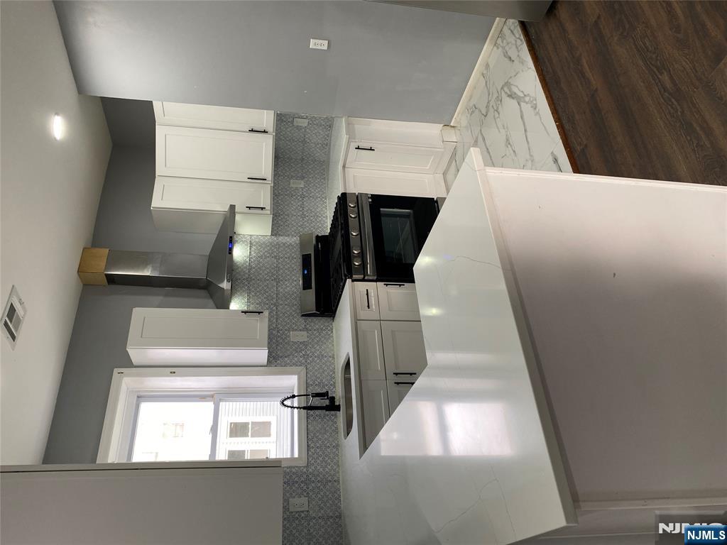 540 South 20th Street, Unit 2 Newark, NJ 07103 - Photo 4 of 13 a kitchen with stainless steel appliances a sink dishwasher a stove and white cabinets with wooden floor