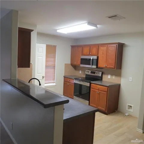 a kitchen with granite countertop a sink cabinets and stainless steel appliances