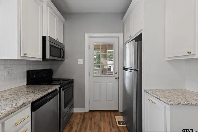 a kitchen with granite countertop a refrigerator stove and microwave