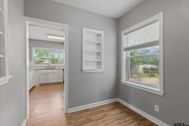 a view of an empty room with a window and wooden floor
