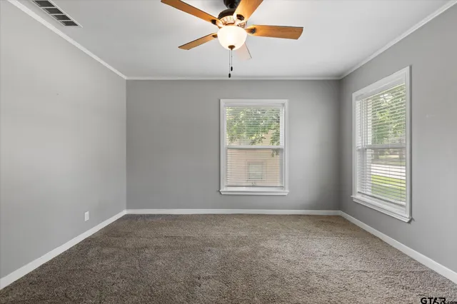 an empty room with windows and fan