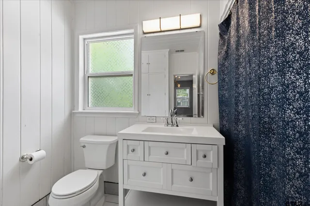 a bathroom with a sink toilet vanity and mirror