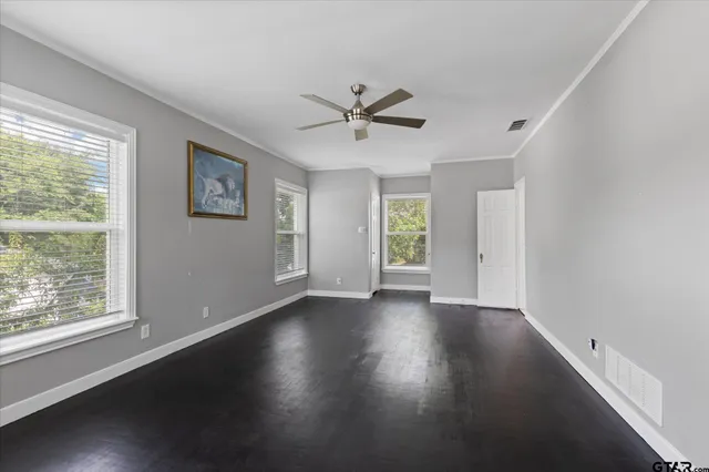 a view of an empty room with a window and wooden floor