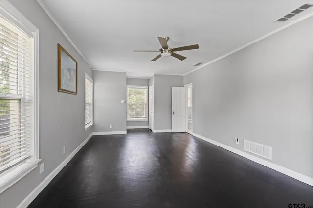 a view of an empty room with a window and wooden floor