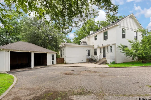 a view of a house with a yard and large tree