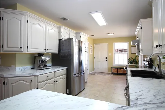 a kitchen with stainless steel appliances kitchen island granite countertop a refrigerator a sink dishwasher a stove with wooden cabinets and floor