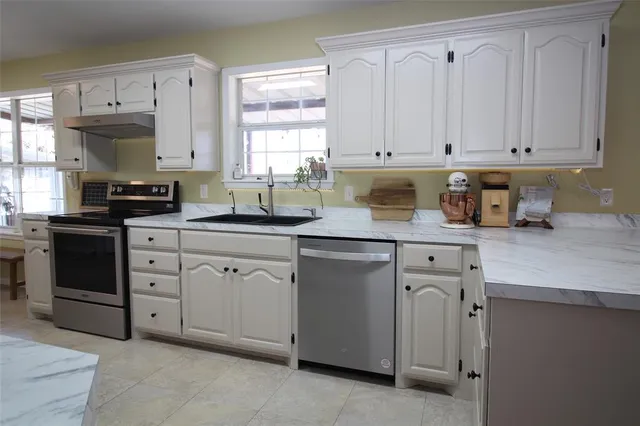 a kitchen with granite countertop white cabinets white stainless steel appliances and sink
