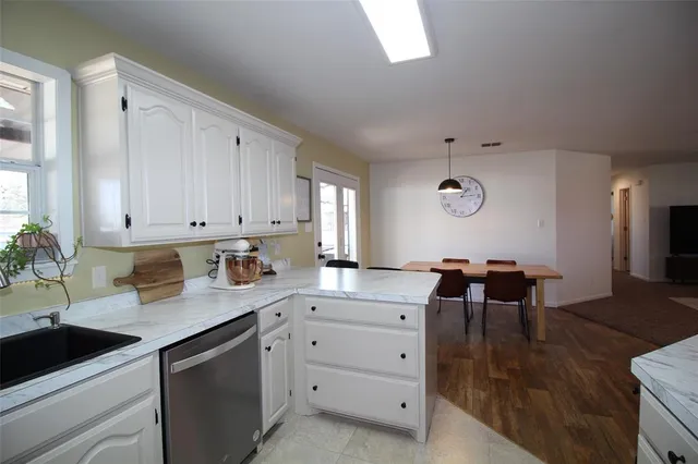 a kitchen with granite countertop cabinets a sink dishwasher and a stove with wooden floor