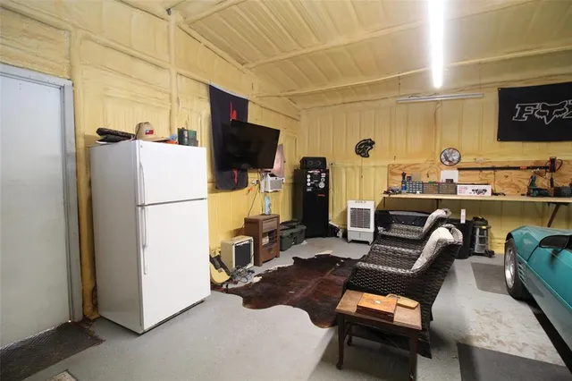 a room with furniture a flat screen tv and a refrigerator