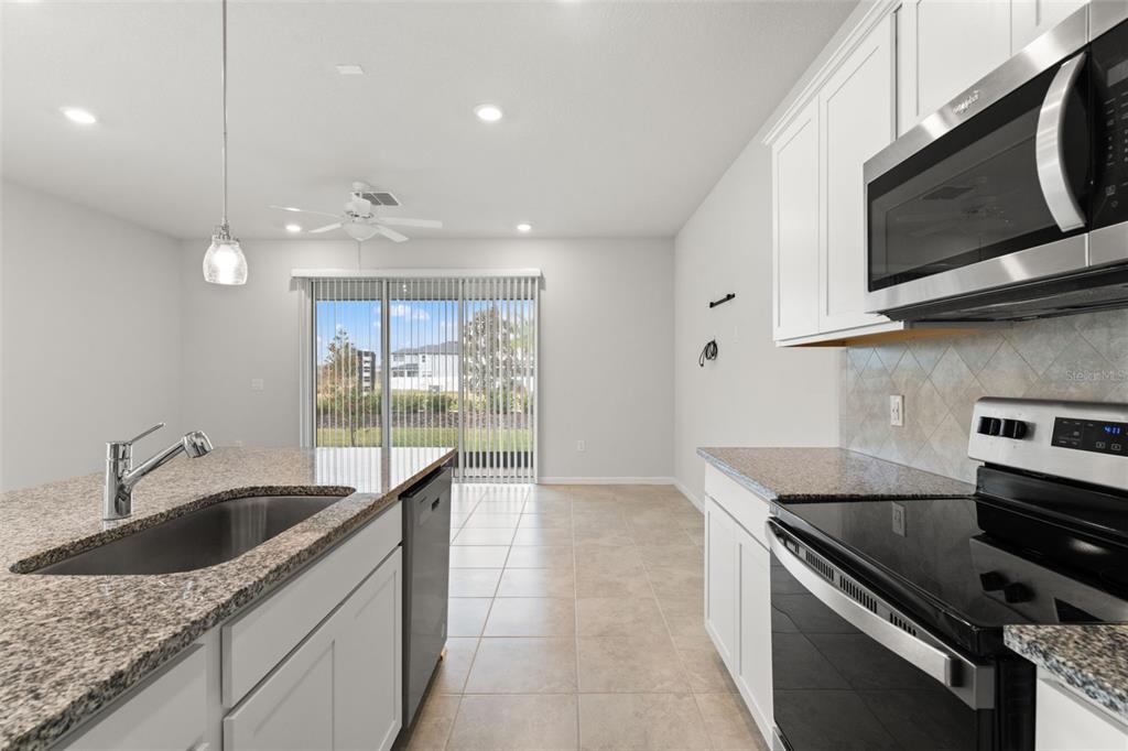 31329 Amberview Bend Wesley Chapel, FL 33545 - Photo 7 of 57 a kitchen with granite countertop a sink a stove and microwave