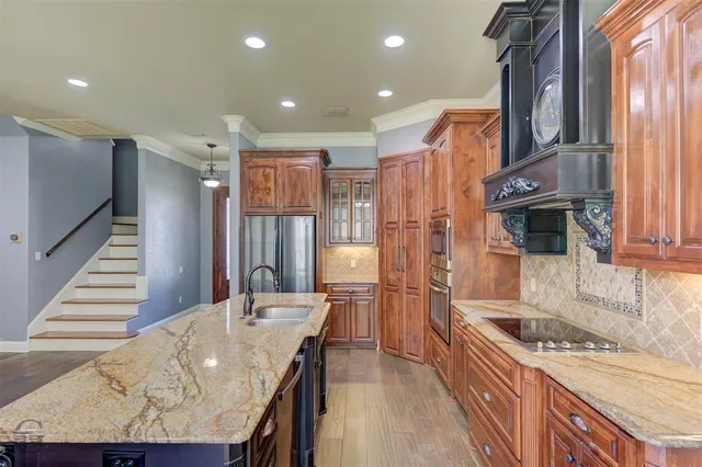 a kitchen with stainless steel appliances granite countertop a sink a stove and a refrigerator