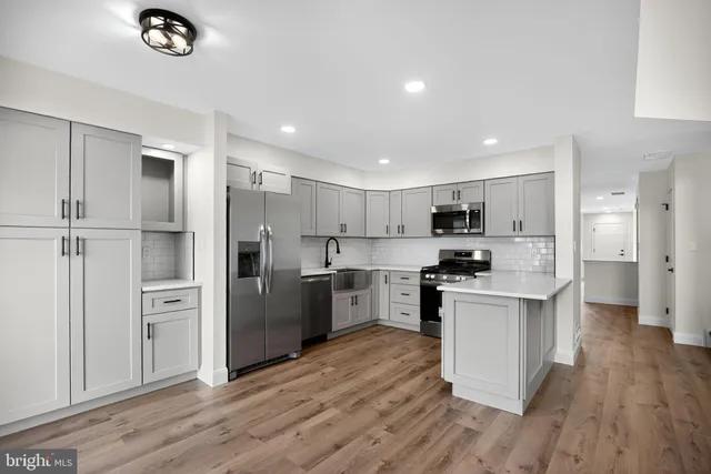 a kitchen with stainless steel appliances a refrigerator a sink dishwasher a stove and white cabinets with wooden floor