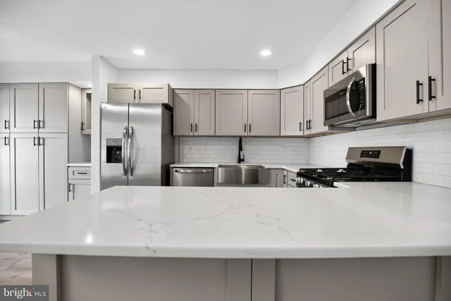 a large white kitchen with stainless steel appliances and a refrigerator