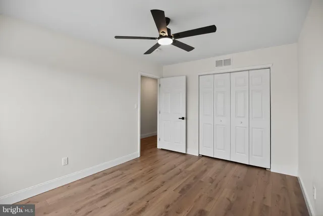 a view of a room with wooden floor and a ceiling fan