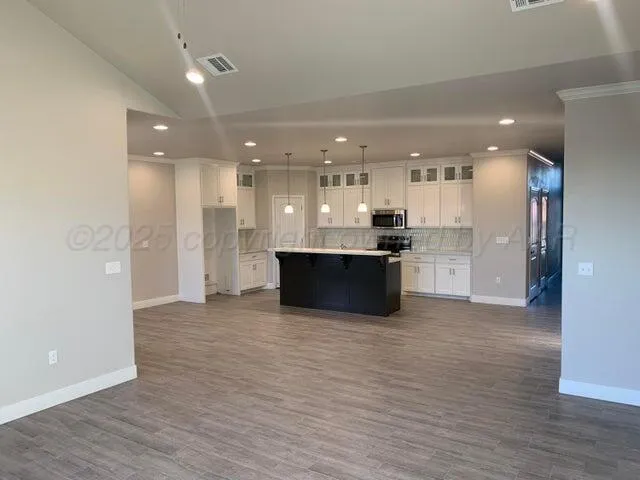 a view of kitchen with kitchen island granite countertop a sink and a refrigerator