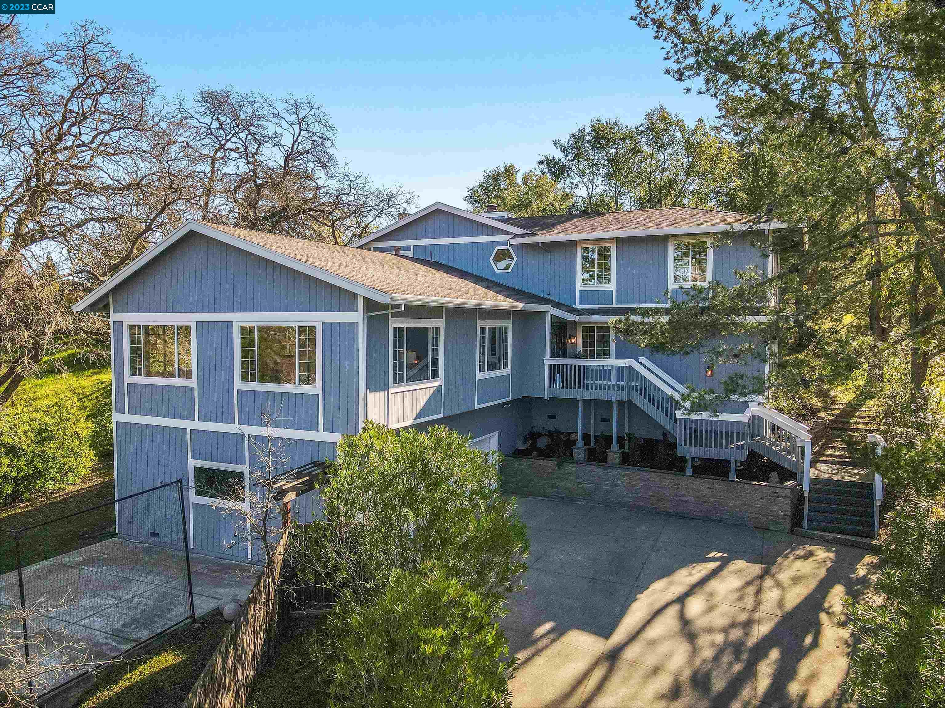 a view of house with yard outdoor seating and covered with trees