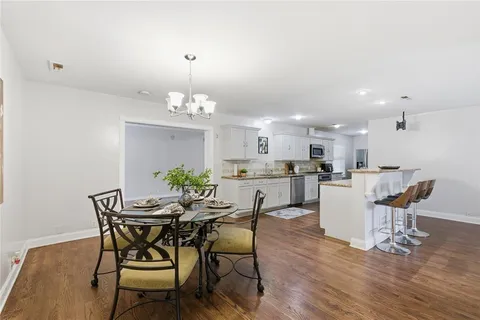 a dining room with wooden floor a chandelier a wooden table and chairs