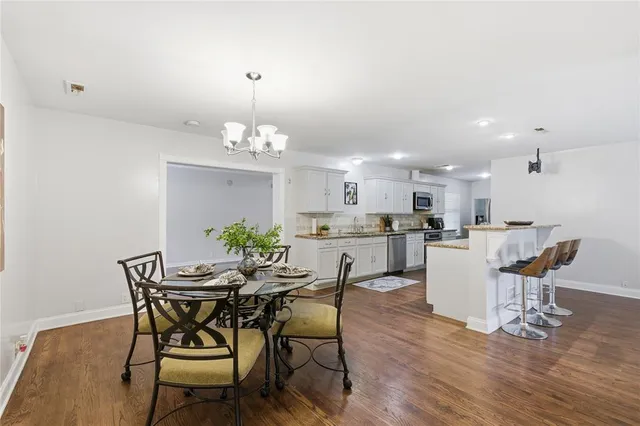 a dining room with wooden floor a chandelier a wooden table and chairs