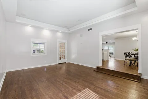 an empty room with kitchen view and wooden floor
