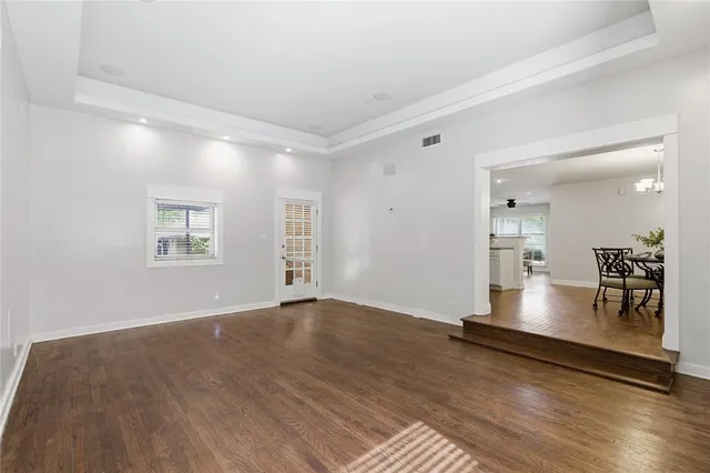 an empty room with kitchen view and wooden floor