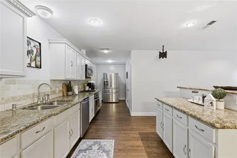 a large kitchen with stainless steel appliances granite countertop a sink and dishwasher with white cabinets