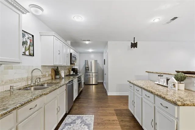 a large kitchen with stainless steel appliances granite countertop a sink and dishwasher with white cabinets