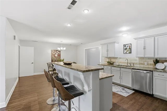 a kitchen with granite countertop a sink counter and chairs