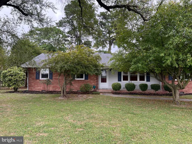a front view of a house with a garden and tree