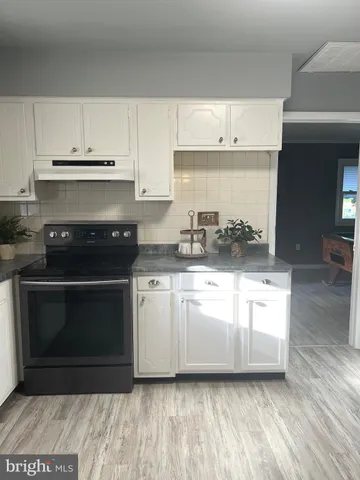 a kitchen with granite countertop a stove a sink and a microwave