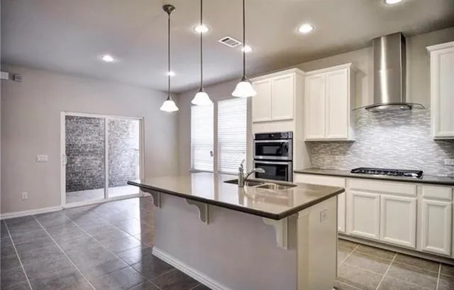 a kitchen with kitchen island granite countertop a stove a sink a center island and cabinets
