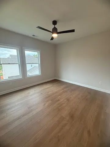 an empty room with windows and ceiling fan