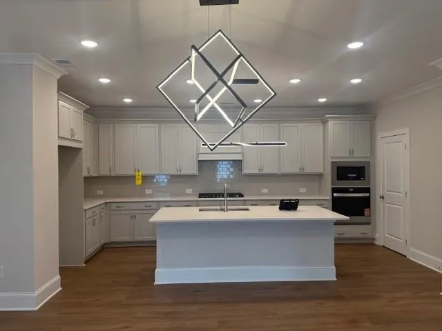 a large kitchen with stainless steel appliances kitchen island granite countertop a stove a sink dishwasher and a refrigerator with wooden floor