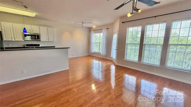 a view of kitchen with stainless steel appliances wooden floor and window